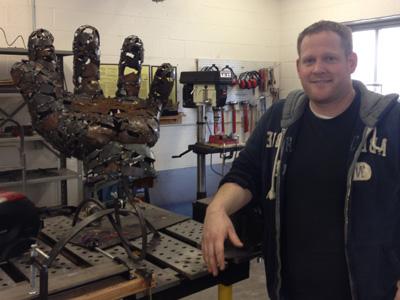 AACC student stands beside his metal sculpture.