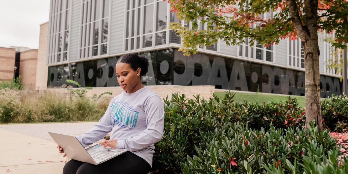 AACC student with laptop outside the library.