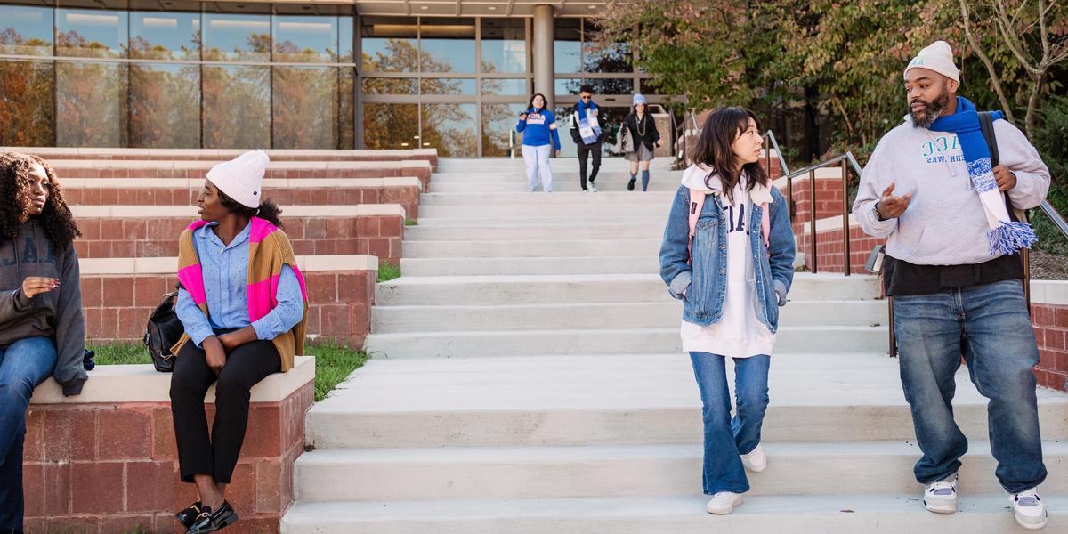 Group of students talking to one another outside in amphitheater.